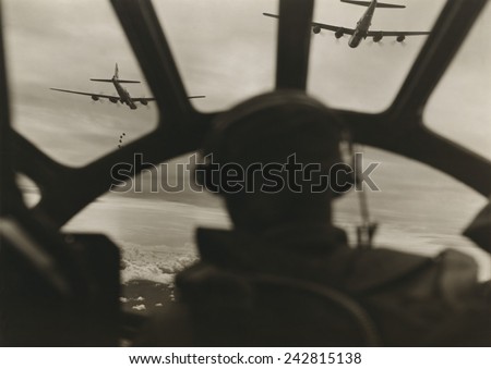 Two B-29 Super-fortresses drop bombs over Malaya as seen from cockpit of third bomber during a run over the important railway yards and repair shops utilized by the Japanese at Kuala Lumpur. 1943-45.