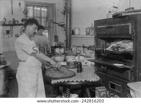 Lebanese-Syrian immigrant pastry cook cutting into a phyllo dough sweet made in the rustic kitchen of in a New York City ethnic restaurant. Ca. 1910.