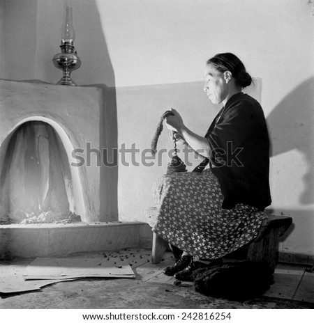Spanish-American women, Maclovia Lopez, hand spinning wool by the light of the fire in New Mexico\'s Taos County. New Mexico has a four century tradition of wool production and weaving.