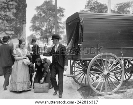 Two women immigrants and a child engage a wagon for transport to their next stop, probably a boarding house or railroad station. Ca. 1900.