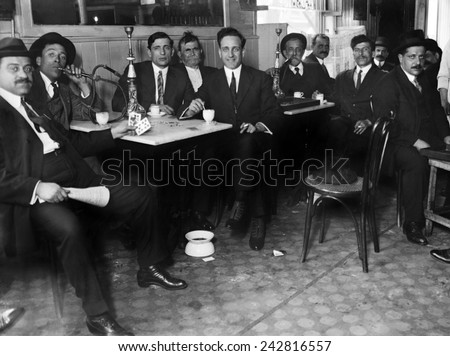 Lebanese-Syrian immigrant men in suits smoking hookahs in a restaurant in the New York City neighborhood, possibly Bay Ridge, Brooklyn. Ca. 1910.
