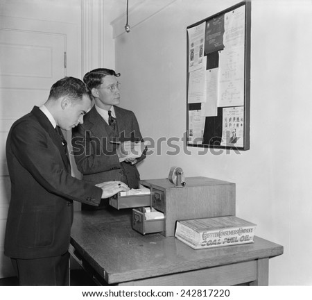 Secret Service agents checking over bulletin board getting the latest criminal news. October 1938.