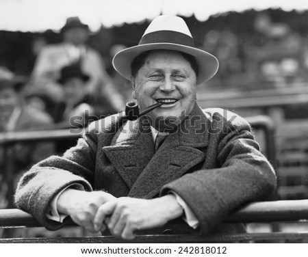 William Wrigley, (1861-1932), president of chewing gum company, watching a game between his Chicago Cubs and the St. Louis Cardinals, in Chicago, Illinois. Ca. 1925.