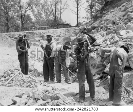 African American convicts in a Southern work gang breaking up rocks with sledge hammers. Ca. 1940.