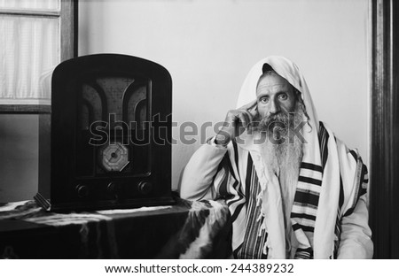 Yemenite Rabbi, in traditional robes and prayer shawl, listening to radio, ca. 1937.