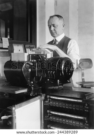 Man loading punch cards into tabulating machine used in 1920 United States census. It was a predecessor of electronic computers, and worked by mechanically reading punch cards with coded information.