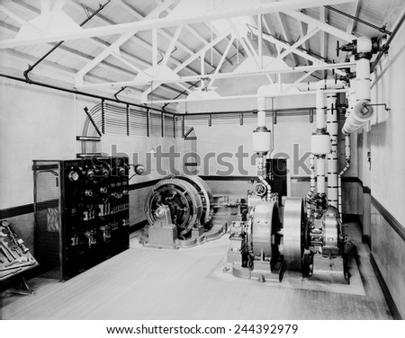 Self-contained electric power station consisting of an engine (right) that powers the rotation of the dynamo (center) that produced electricity. At left is a simple control and switch panel.