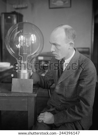 C.W. Mitman, Head Curator, Department of Engineering and Industries of the Smithsonian Institute, holds a giant light bulb. For contrast a midget bulb is placed beside it. March 1923.