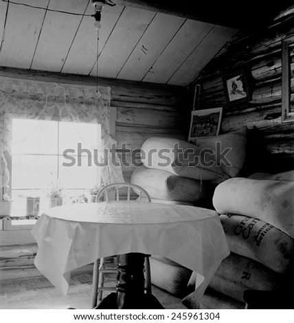 Interior of an Idaho farmer\'s two-room log home. The sacks of alfalfa seed were stored in the home while the farmers waited for a better price. October 1939 photo by Dorothea Lange.