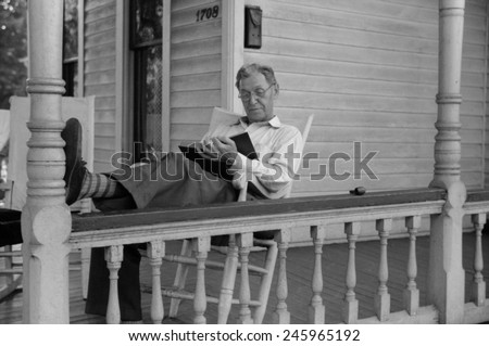 Reading a good book. Middle age man reading on his front porch on a Sunday afternoon in July 1941. Vincennes, Indiana.