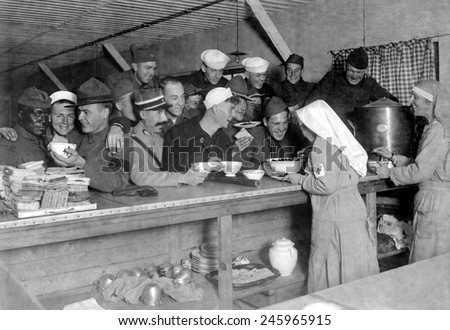 An unusual WWI scene of an African American soldier being served with American and French service men. American Red Cross canteen lunch bar at Bordeaux, France. Oct. 1918.