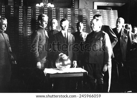 Secretary of War Newton D. Baker, wearing a blindfold, initiates the second draft of WWI. He draws the first number, 246, out of a glass bowl to start the draft. June 1918.