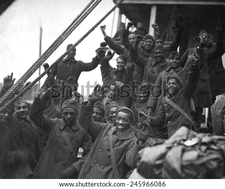 African Americans, members of 369th Colored Infantry, wave from a troop ship as they arrive back in New York City. The regiment was nicknamed the Harlem Hellfighters and the Black Rattlers. Ca. 1919.