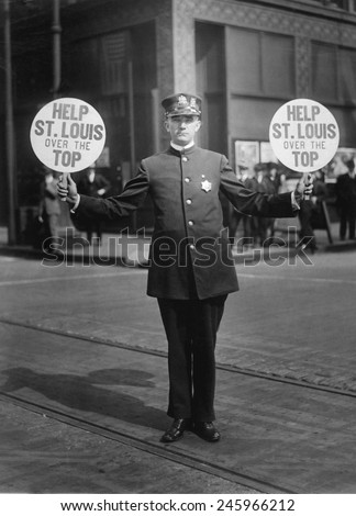 Fourth Liberty Loan Campaign during WWI. St. Louis traffic policeman using 4th Liberty Loan fans for signals. Fans read, \'Help St. Louis over the Top.\' 1918.