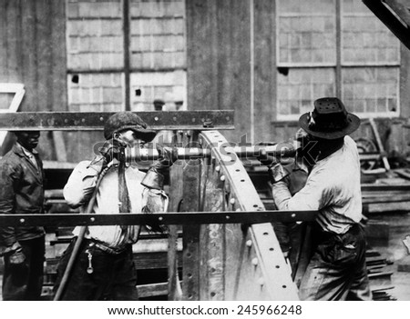 Charles Knight (left) who won the prize offered by the London Mail for expert rivet driving. He drove 4,875 rivets in nine hours in a Government shipyard. WWI. Ca. 1918.