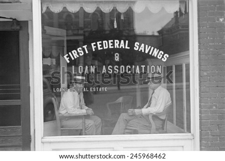 Two businessmen sit behind the storefront window of Marion, Ohio, Savings and Loan Association. Depression era Federal Home Loan Bank Act of 1932 made low-cost funding available for mortgage lending.