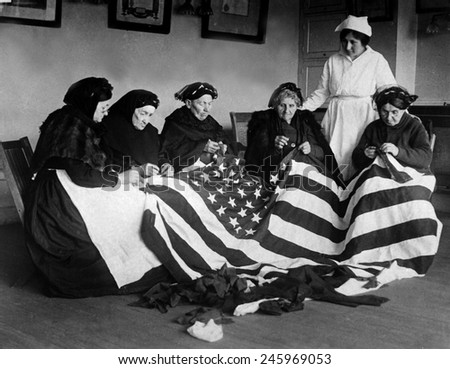 Patriotic elderly immigrant women making a flag during WWI. They are from Eastern Europe countries of Hungary, Galicia, Russia, Germany, and Rumania. Ca. 1918.