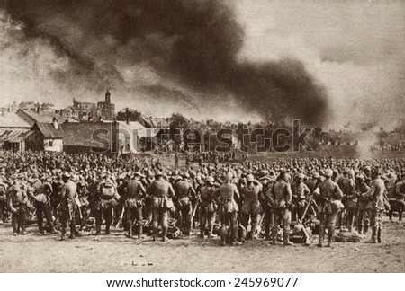 WWI. German troops gathered after driving the Russians from Garlice, Galicia. The smoke is from the town that was put to the torch by the Germans. 1915.