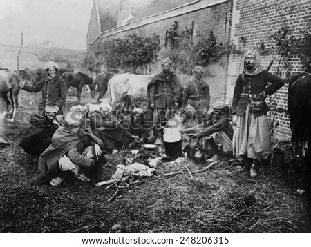 WW1 North African Spahis in camp at Arsy after battle in France in 1914. The light cavalry soldiers gather around a fire in their distinctive uniforms with baggy pants, turbans, and capes. 1914.