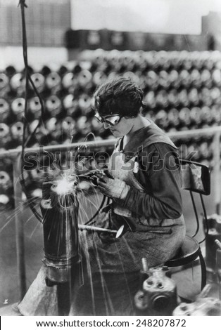 America WW1 woman arsenal worker. 1918. She is welding a water jacket for a machine gun. Thewaterjacket keeps the guns from overheating.