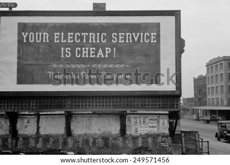 \'Your Electric Service is Cheap\' reads a 1930s billboard. Posted by the Nebraska Power Company.