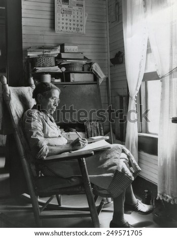 Elderly African American woman writing in a rocking chair, Putnam, Georgia, May 1941.