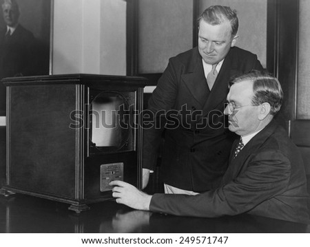 Labor secretary William Doak and W.W. King, examining a 1931 television receiver at the Labor Department. The magnifying screen aided viewing the small round TV image.