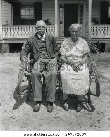 Prosperous African American farm couple, Nansemond, Virginia, May 1932. They are seated in front of a tidy house with unworn clothing. Photo by George Ackerman.