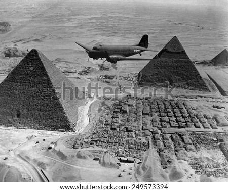American Air Transport Command plane flies over the pyramids of Egypt. Flights from the U.S. supplied strategic battle zones of North Africa during World War 2. 1943.