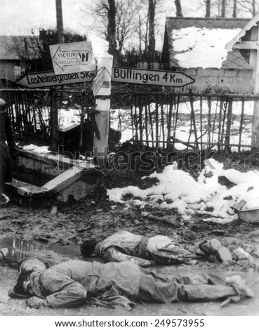 American soldiers, stripped of equipment, lie dead, face down in Belgium. The soldier in the foreground has bare feet. Dec. 12-31, 1944. Battle of the Bulge.