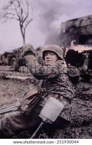German soldier waving members of unit forward in the first days of the Battle of the Bulge. In the background are burning U.S. vehicles. Dec. 16-22, 1944. Belgium. B&W Photo with oil color.