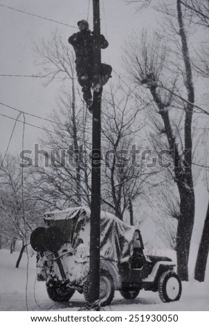 U.S. Army Signal Corp lineman repairing damaged phone lines in France. Winter of 1944-45, World War 2. B&W Photo with oil color.