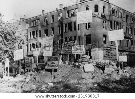 Bombed-out building in Wittenberg Platz, Berlin. Many of the signs posted give directions to merchants\' new locations. Photo was taken by Danish photographer Hans Martin Herloff, Ca. March 1945.