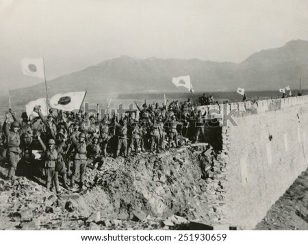 Japanese soldiers celebrate the capture of Nanking, China. A detachment of Japanese troops on the high wall of Nanking give a Bauzai salute. Flags of Japan is waved in victory. Ca. Dec. 13-31, 1937.