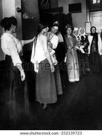 Women immigrants undegoing a physical examination, Ellis Island, New York. ca. November 1910.
