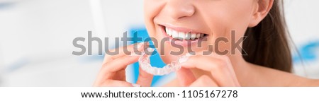 Woman wearing orthodontic silicone trainer. Invisible braces aligner. Mobile orthodontic appliance for dental correction.
