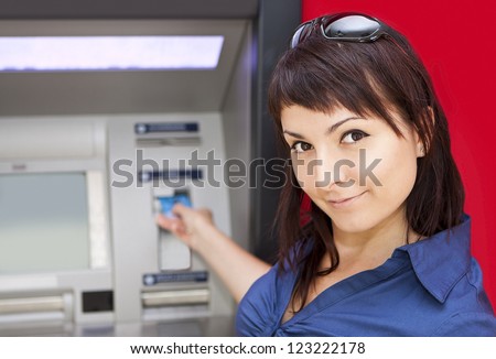 Beautiful woman using credit card, she is withdrawing money from an ATM machine.