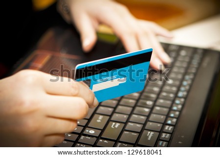 Hands entering credit card information into a laptop