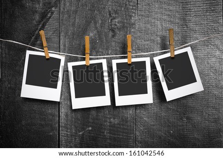 four photo paper attach to rope with clothes pins on wooden background