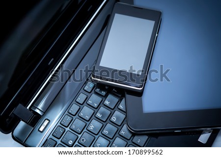 Closeup picture of a keyboard with a phone and tablet lying above