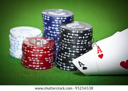 Gambling chips, ace of diamonds and king of spades on green poker cloth.