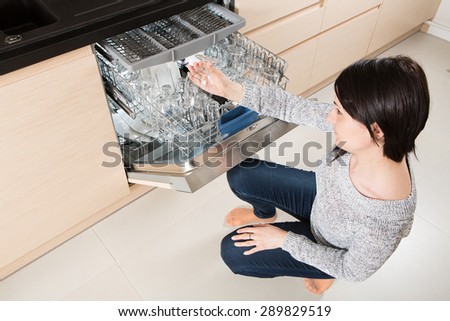 Woman using a dishwasher in a modern kitchen. Domestic appliance.