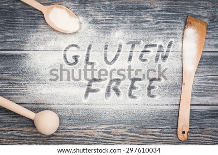 Gluten free word written on flour. Table wooden background.