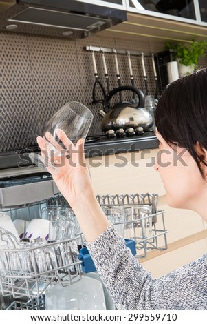 Woman using a dishwasher in a modern kitchen. Domestic appliance.