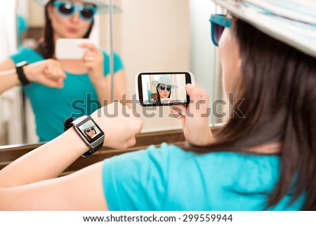 Woman taking self portrait selfie photo and sends it to smartwatch.