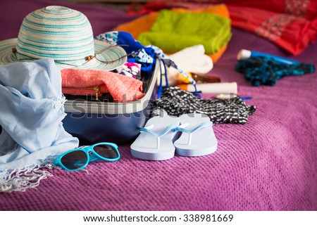 Open suitcase with clothing in the bedroom. Summer holiday concept.