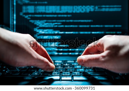 Hacker using laptop. Lots of digits on the computer screen.