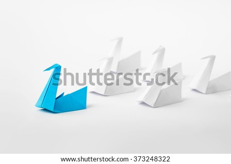 Leadership concept with origami paper bird leading among white.