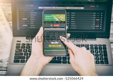 betting bet sport phone gamble laptop over shoulder soccer live home website concept - stock image
