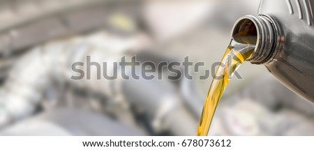 Pouring oil to car engine. Fresh oil poured during an oil change to a car.